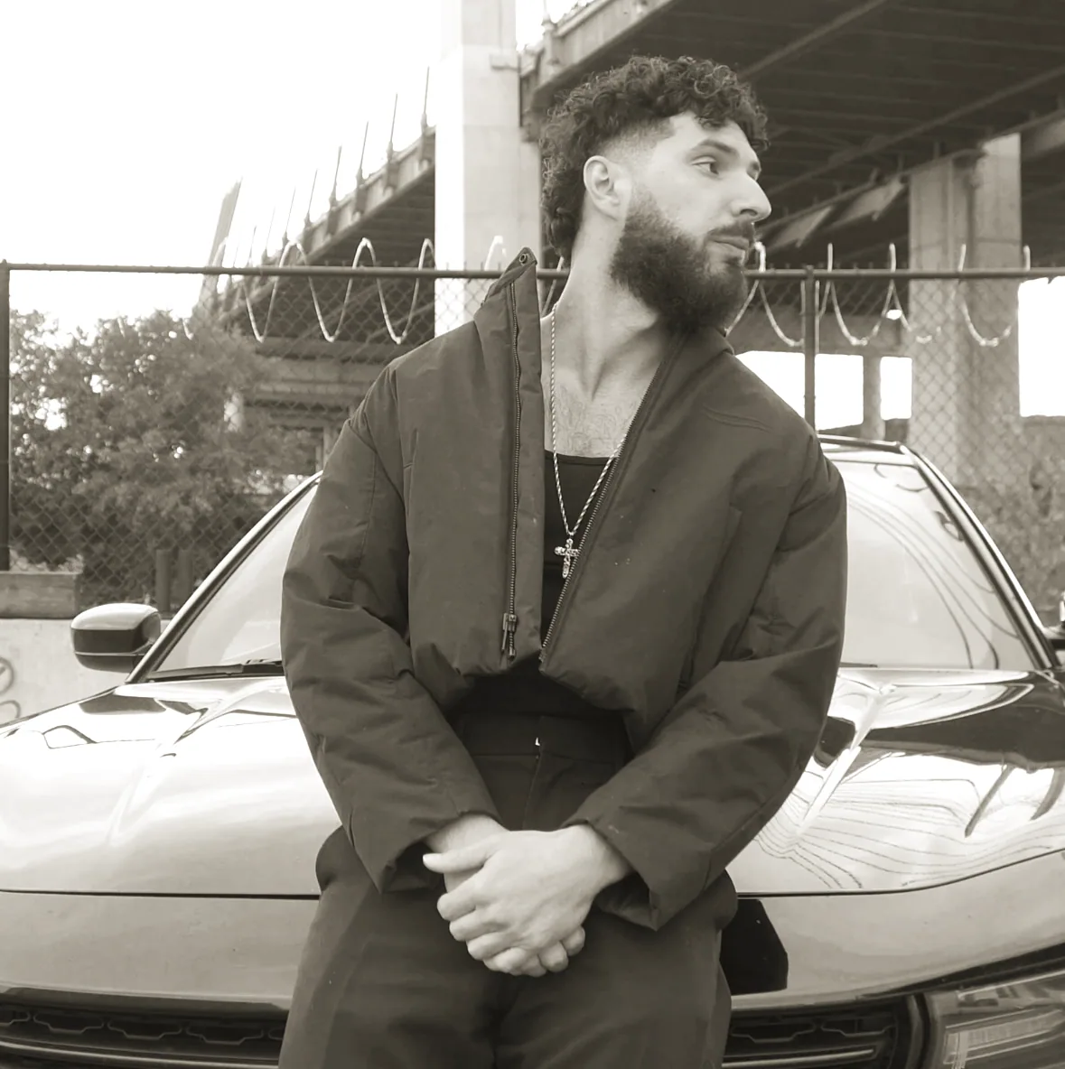 Young Benny by a black car under a bridge - New Jersey