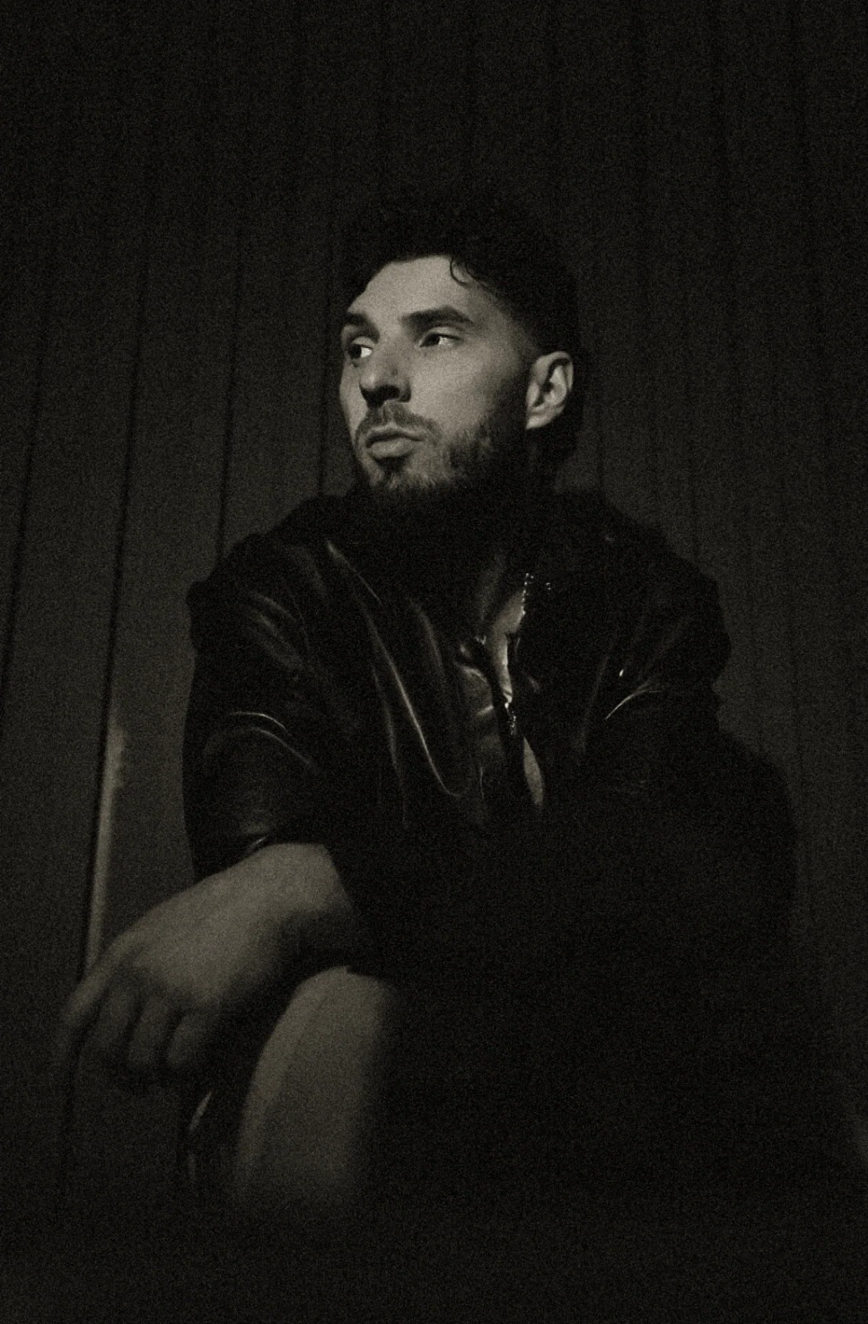 Young Benny in a leather jacket under low light - cinematic press portrait